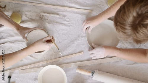 Girl sculpts clay dishes. Top view.