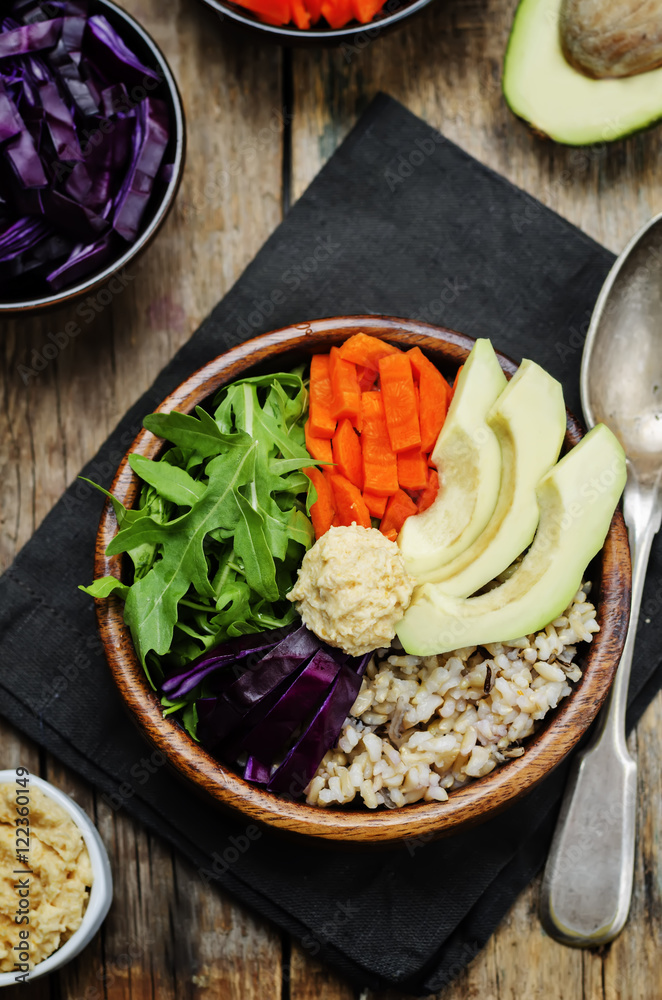 Rice bowl with red cabbage, carrots, avocado, arugula and hummus