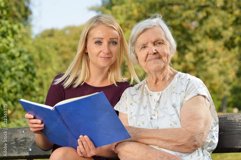 Young woman reading a book elderly woman in the park.
