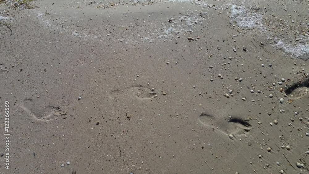 Women human footprints on a sandy beach, the sound of waves Women human footprints on a sandy beach, the sound of waves