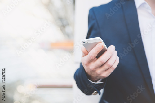 Businessman with telephone in hand and holding a newspaper. Stylish man at the railway station in a blue jacket.