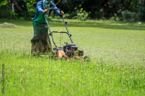 A worker mowing grass in the garden