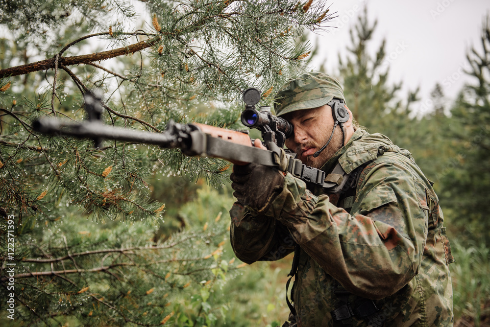 Fototapeta premium army soldier holding sniper rifle with scope and aiming in forest. war, army, technology and people concept