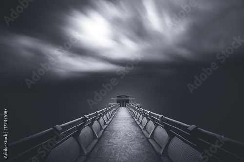 Perspective of road towards a tower with cloud moving blown by strong wind.