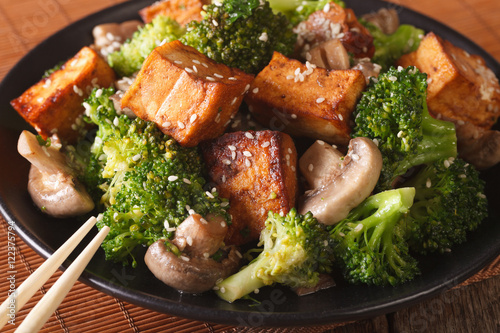 Vegetarian food: fried tofu with broccoli, mushrooms and sesame close-up. horizontal 