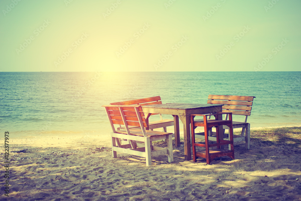 wooden desks and chairs  on beach with sun light, vintage tone