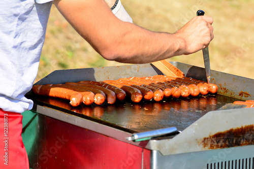 Koch beim Grillen von Käsekrainer auf einer Grillplatte photo