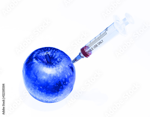 Abstract representation of danger food: Genetically modified blue apple injected with syringe with soft shadow on white background