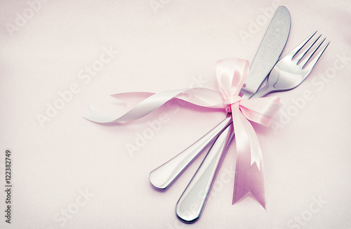 White plate, fork and knife on light background.