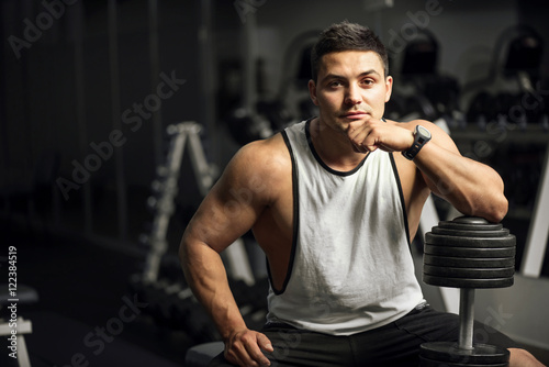 Handsome well built weightlifter sitting thoughtfully