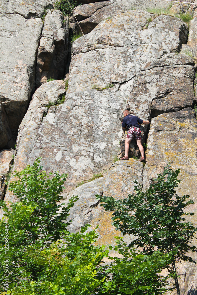 Man climber climbing up on a rock
