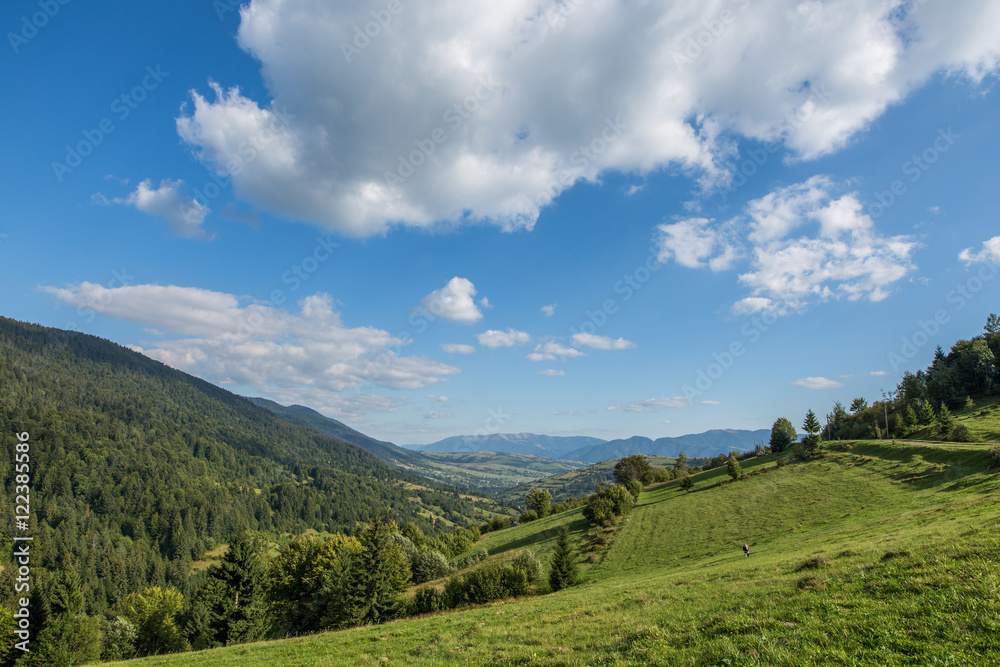 Green meadow, mountain and sky with clouds