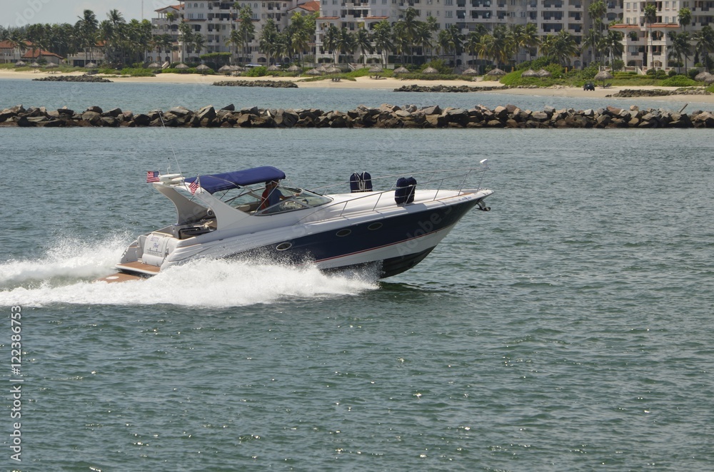 Obraz premium An upscale cabin cruiser speeding by an upscale condominium complex in southeast florida