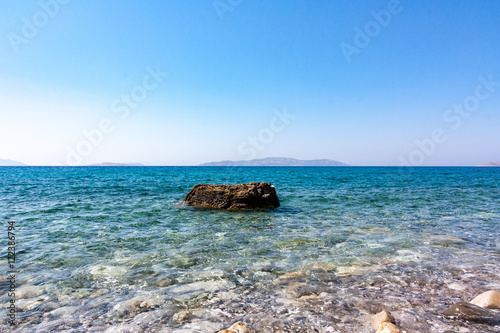 Fototapeta Naklejka Na Ścianę i Meble -  Single rock in clear sea water with blue sky