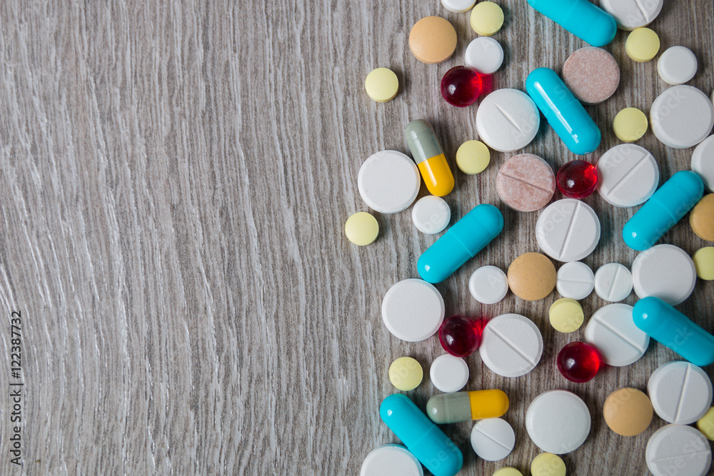 lot of colorful medication and pills from above on grey wooden background. Copy space. Top view, frame. Painkillers, tablets, generic , drugs. lot of colorful medication and pills from above on grey wooden background. Copy space. Top view, frame. Painkillers, tablets, generic , drugs.