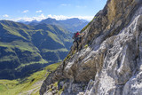 Jugendlicher klettert gesichert eine Felswand hinauf