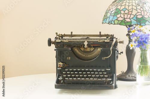 black vintage typewriter with retro lamp, copy space on wall