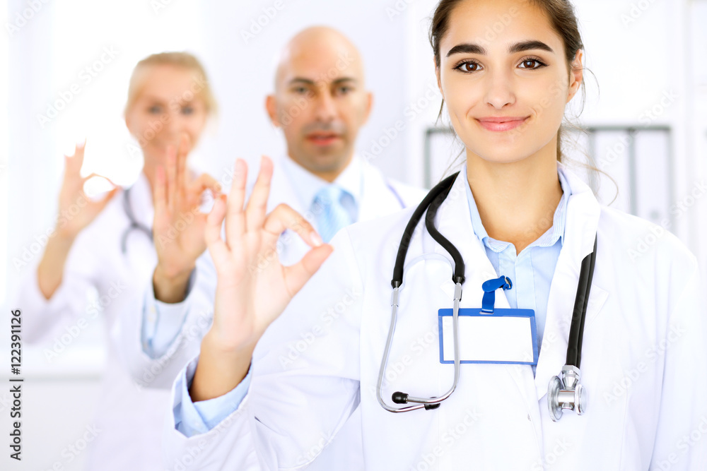 Happy doctor woman with medical staff at the hospital. Thumbs up and Ok sign! Happy doctor woman with medical staff at the hospital. Thumbs up and Ok sign!