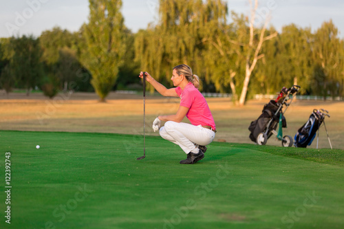 female golfer Golfing On Golf Course Lining Up Putt On Green