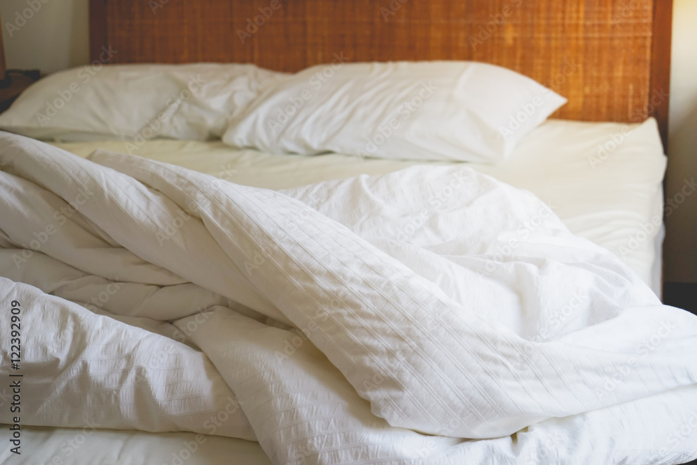 Messy white bedding sheets in selective focus on bed with morning light Messy white bedding sheets in selective focus on bed with morning light
