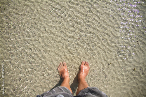 Man's feet in sea water background