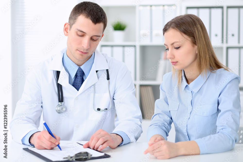 Doctor and patient sitting at the table in medical cabinet. High level and quality medical service concept. Doctor and patient sitting at the table in medical cabinet. High level and quality medical service concept.