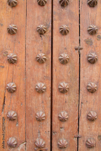 Part of the old wooden gate decorated with metal elements.