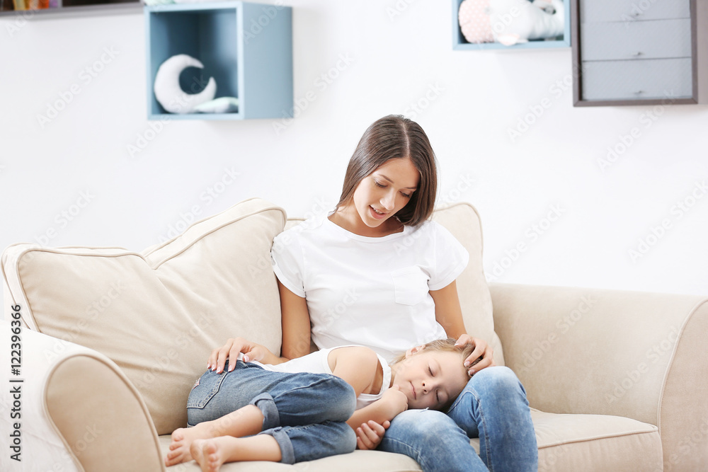 Cute girl lying on mothers knees at home