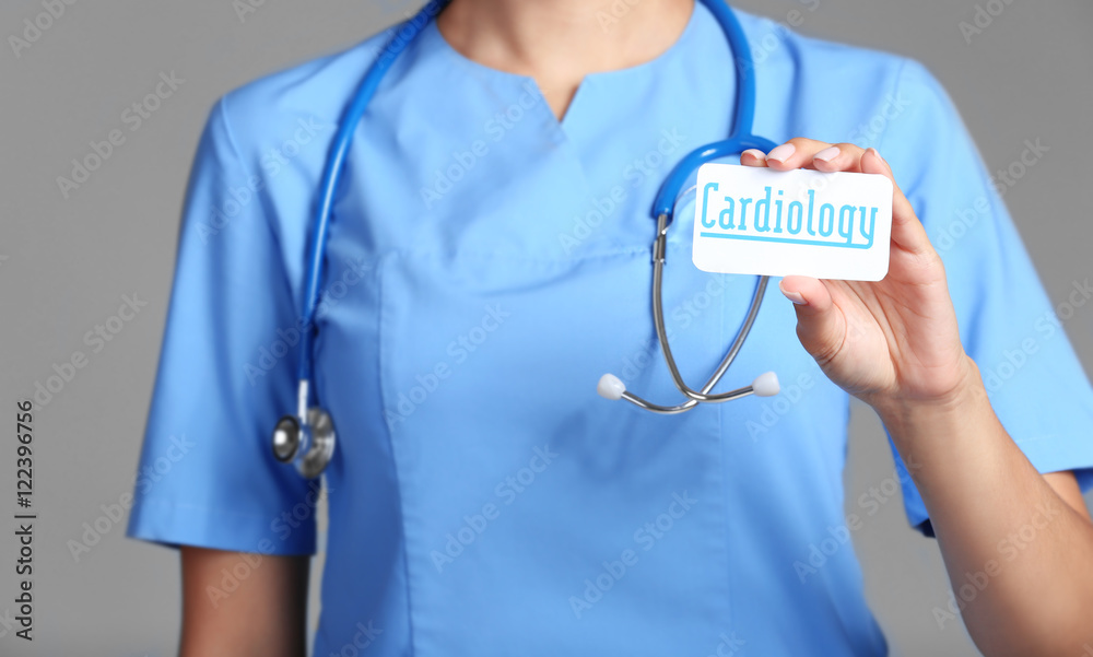 Doctor hand holding card with word CARDIOLOGY on grey background Doctor hand holding card with word CARDIOLOGY on grey background