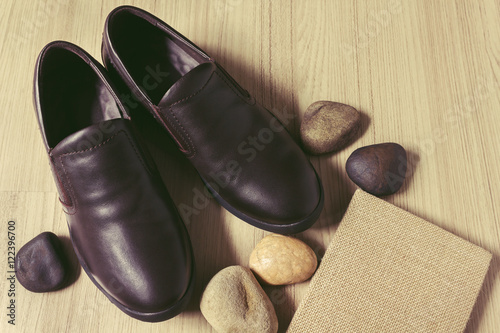 Man brown leather shoes with note book or diary with stone pebble