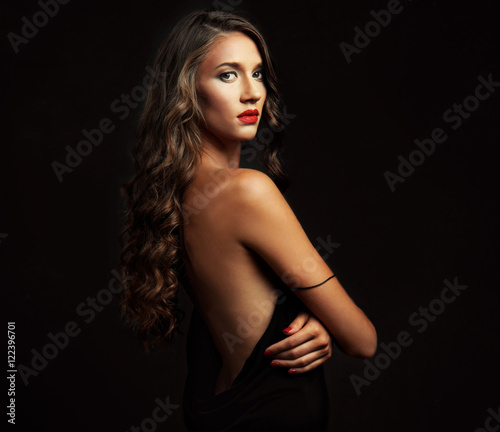 Beautiful young woman with make up and long wavy hair on black background