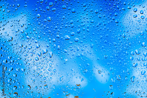 Abstract texture. Water drops on glass with sky and clouds background