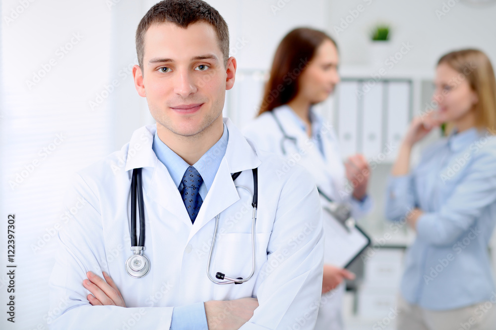 Friendly male doctor on the background with patient in hospital. High level and quality medical service concept. Friendly male doctor on the background with patient in hospital. High level and quality medical service concept.