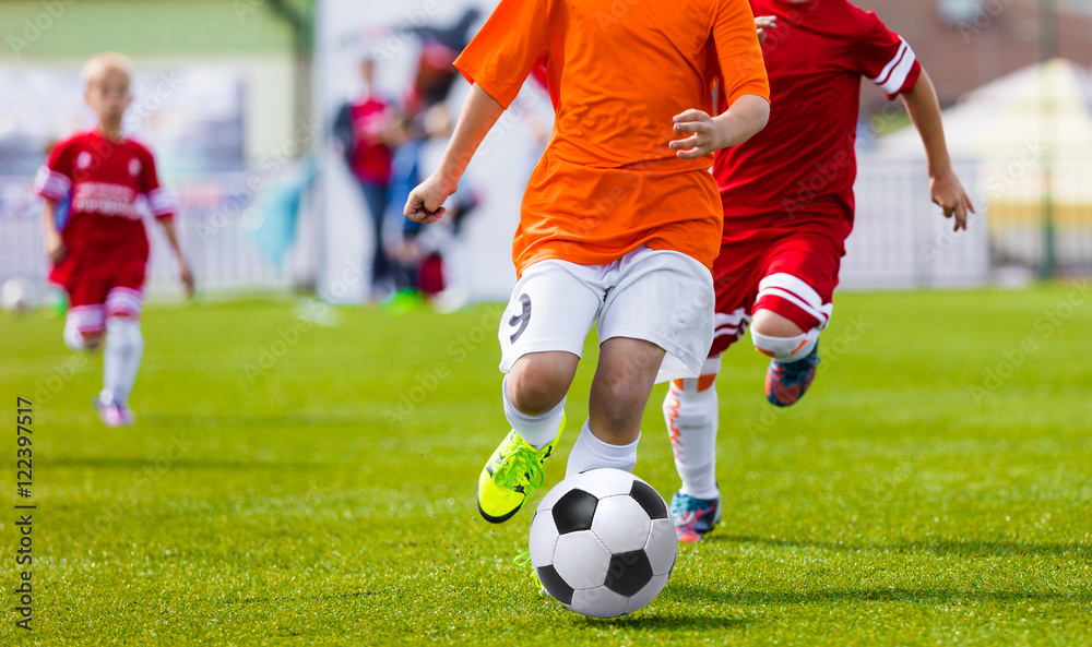 Young soccer football players kicking soccer ball on sports field. International soccer league tournament for youth football teams Young soccer football players kicking soccer ball on sports field. International soccer league tournament for youth football teams
