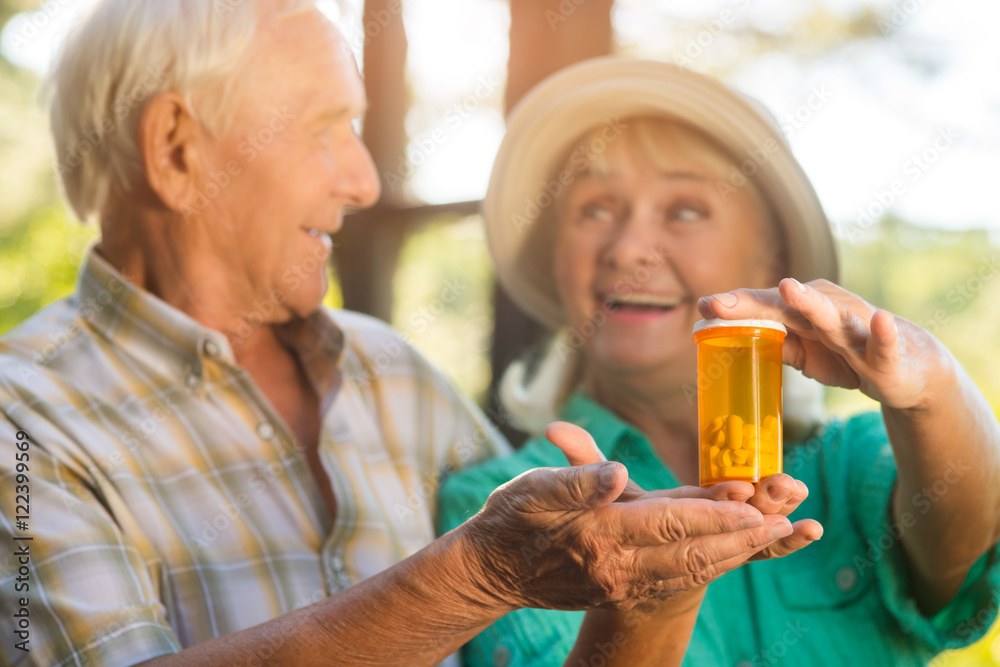 Couple with pill bottle. Smiling senior man and woman. Drug with vitamins and minerals. Restore your health. Couple with pill bottle. Smiling senior man and woman. Drug with vitamins and minerals. Restore your health.