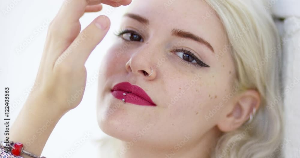 Beautiful young blond woman with a pierced lip wearing crimson lipstick smiling at the camera close up head shot with focus to her mouth Beautiful young blond woman with a pierced lip wearing crimson lipstick smiling at the camera close up head shot with focus to her mouth
