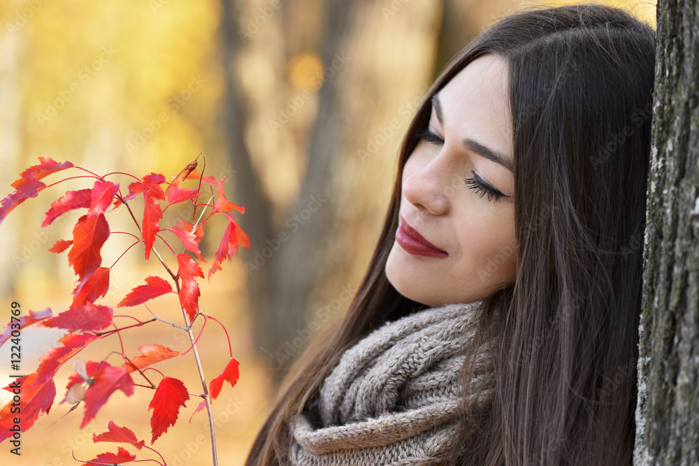 Naklejka premium Girl with a branch of a tree with red leaves in autumn park