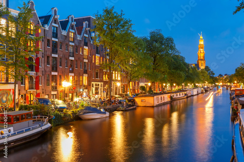 Fototapeta Naklejka Na Ścianę i Meble -  Night city view of Amsterdam canal Prinsengracht with houseboats and Westerkerk church, Holland, Netherlands.