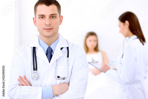 Friendly male doctor on the background with patient in the bed