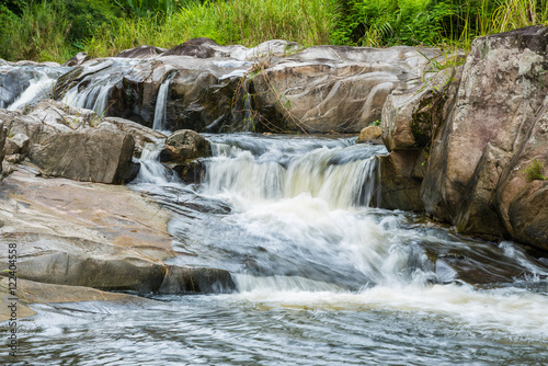 Waterfall cascades flowing over flat rocks in forest.