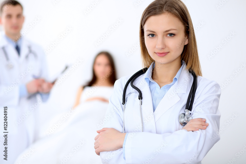 Friendly female doctor on the background with patient in the bed and his physician Friendly female doctor on the background with patient in the bed and his physician