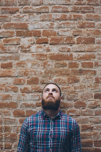 young man with beard against background of an old brick wall