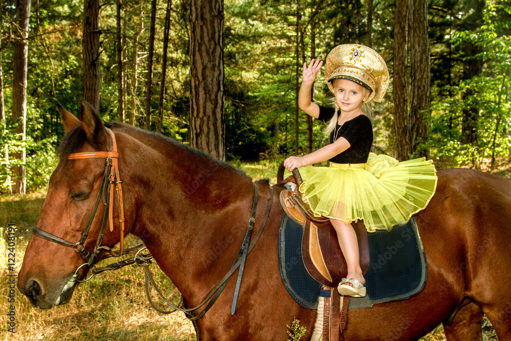 little girl riding a horse in the forest