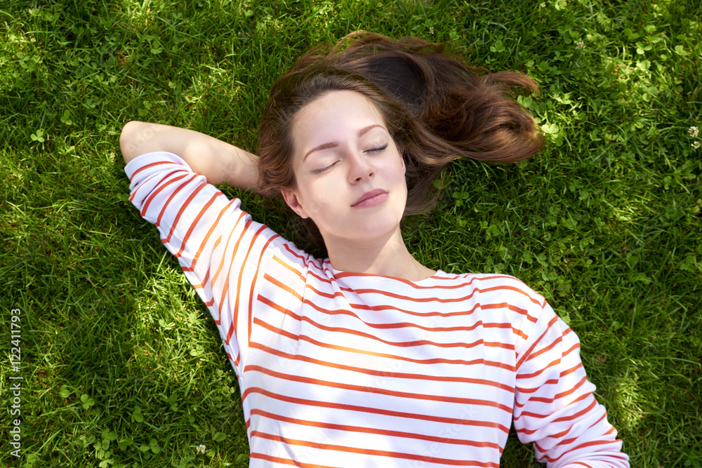 Beautiful girl lying in the grass. Shot from above of a beautiful young woman relaxing while lying in the grass at summer. Beautiful girl lying in the grass. Shot from above of a beautiful young woman relaxing while lying in the grass at summer.