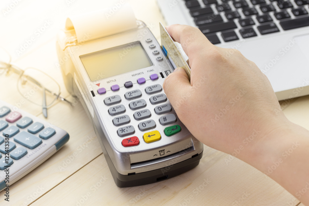 Credit Card Terminal or EDC on cashier wooden table in the store with calculator, pen, pencil, digital tablet and glasses on wooden background with copy space. Credit Card Terminal or EDC on cashier wooden table in the store with calculator, pen, pencil, digital tablet and glasses on wooden background with copy space.