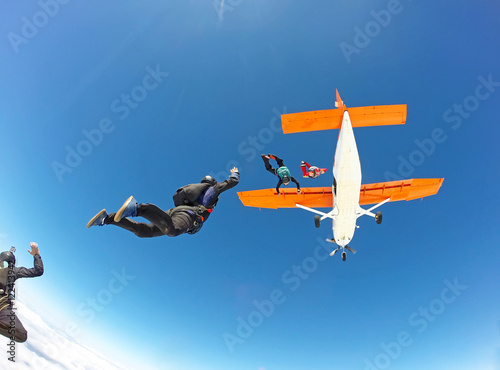 Skydivers jumping from the orange plane