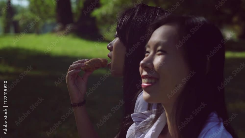 Portrait happy girls eating bun and drinking coffee in red paper cup. Asian woman enjoy snack outdoors and talking. Smiling friends enjoy breakfast in city. Portrait happy girls eating bun and drinking coffee in red paper cup. Asian woman enjoy snack outdoors and talking. Smiling friends enjoy breakfast in city.