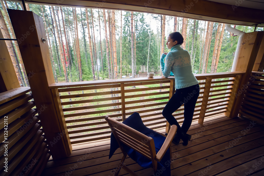 girl in a blue sweater stand and drinking tea
