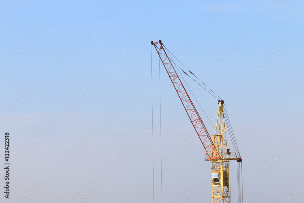 Part of yellow stationary hoist on construction site, blue sky a