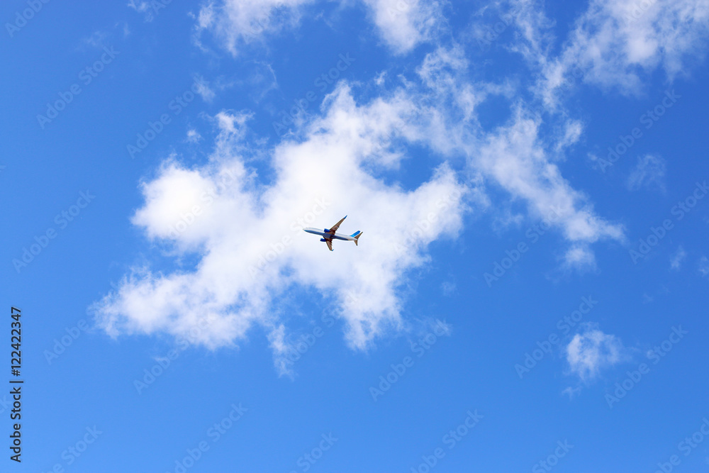 Under view of modern passenger airliner in blue sky with white c Under view of modern passenger airliner in blue sky with white c